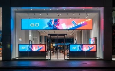 Ultra-wide bar digital signage display installed in a retail storefront showing promotional content.