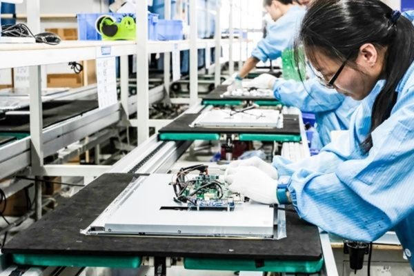 Technician assembling LCD display modules on automated production line