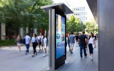 Outdoor digital signage kiosk with a high brightness LCD display on a city sidewalk in bright daylight
