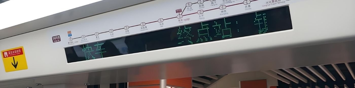 Metro station interior with an ultra-wide passenger information display showing line map and next-station message