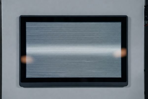 Oscilloscope measuring power ripple on an LCD display module while a gray test pattern shows subtle flicker banding