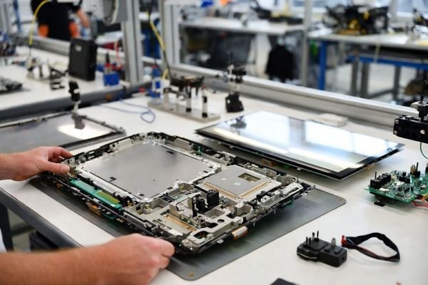 Large LCD display module (≥12-inch) being integrated with cover glass, touch panel, and mounting structure on an engineering workbench.