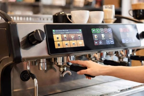 A commercial coffee machine with a clear LCD touch panel in a bright service environment
